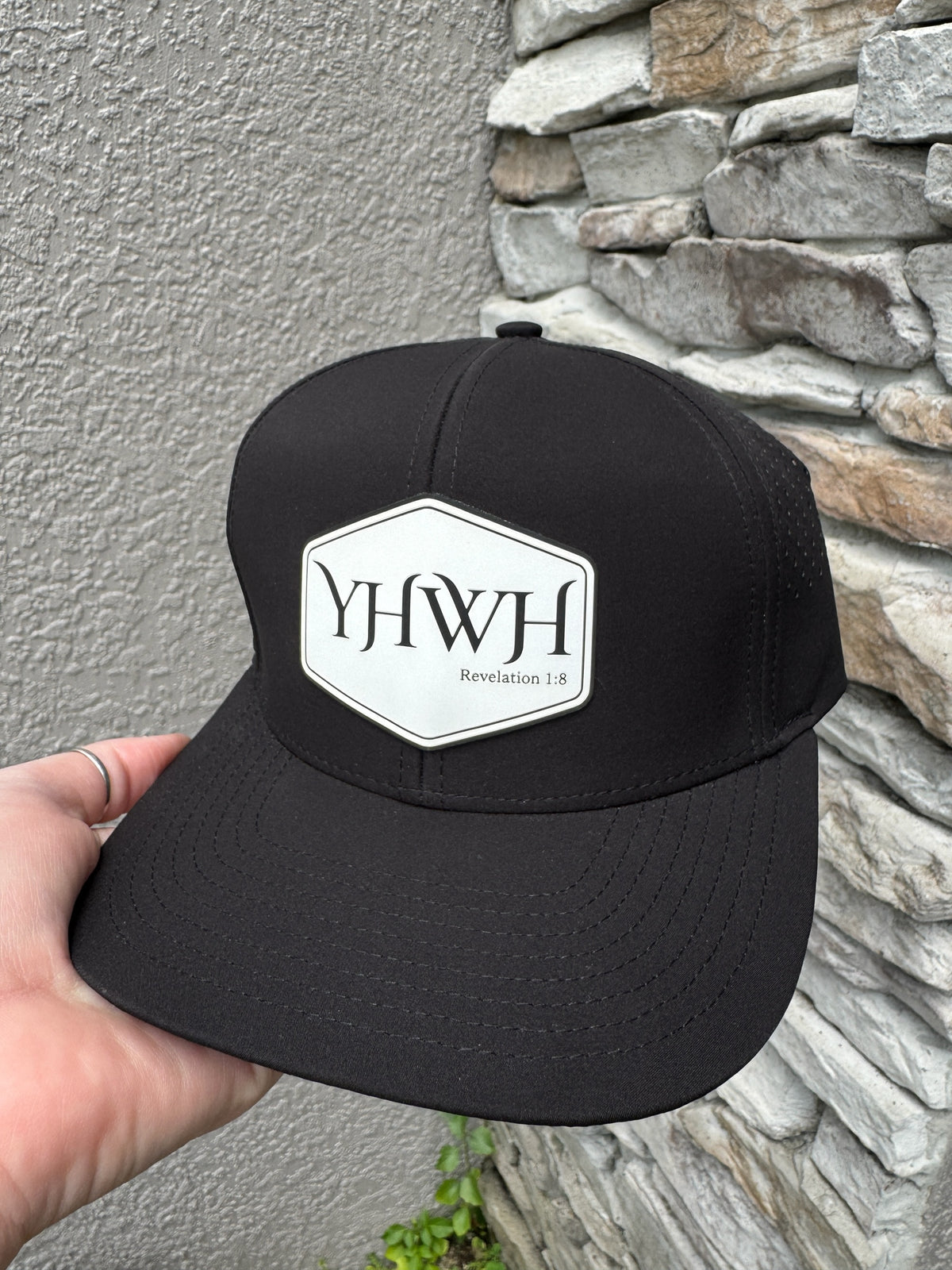 Lucas Made black performance baseball cap with a hexagonal YHWH Revelation 1:8 patch and breathable side panels.